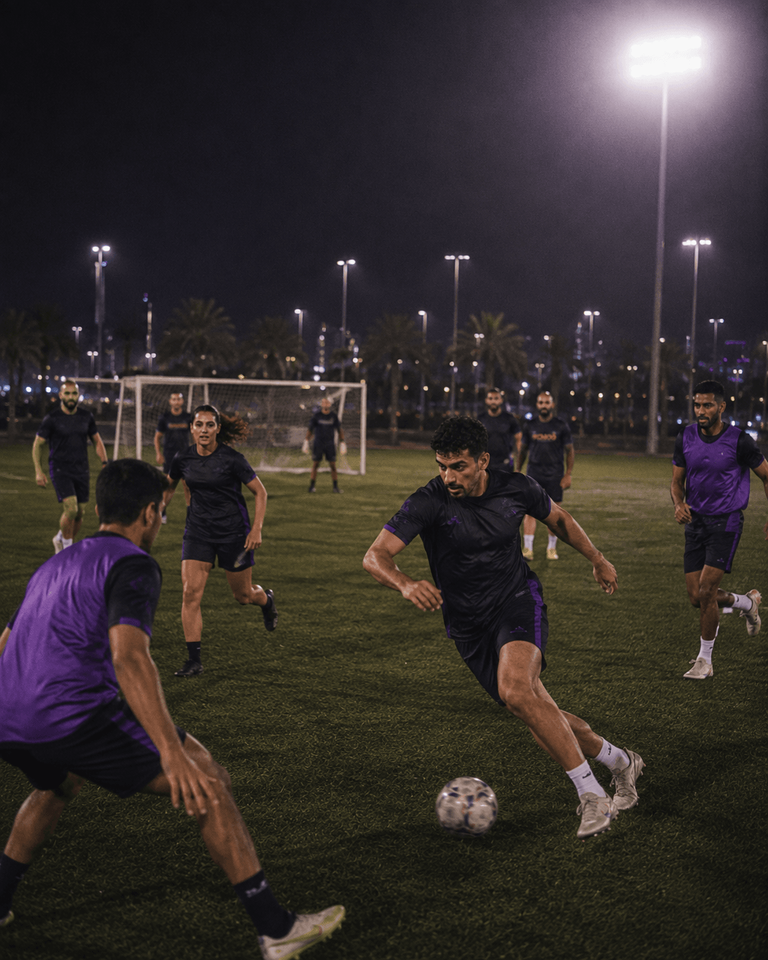 Players competing in a small-sided football match under the floodlights